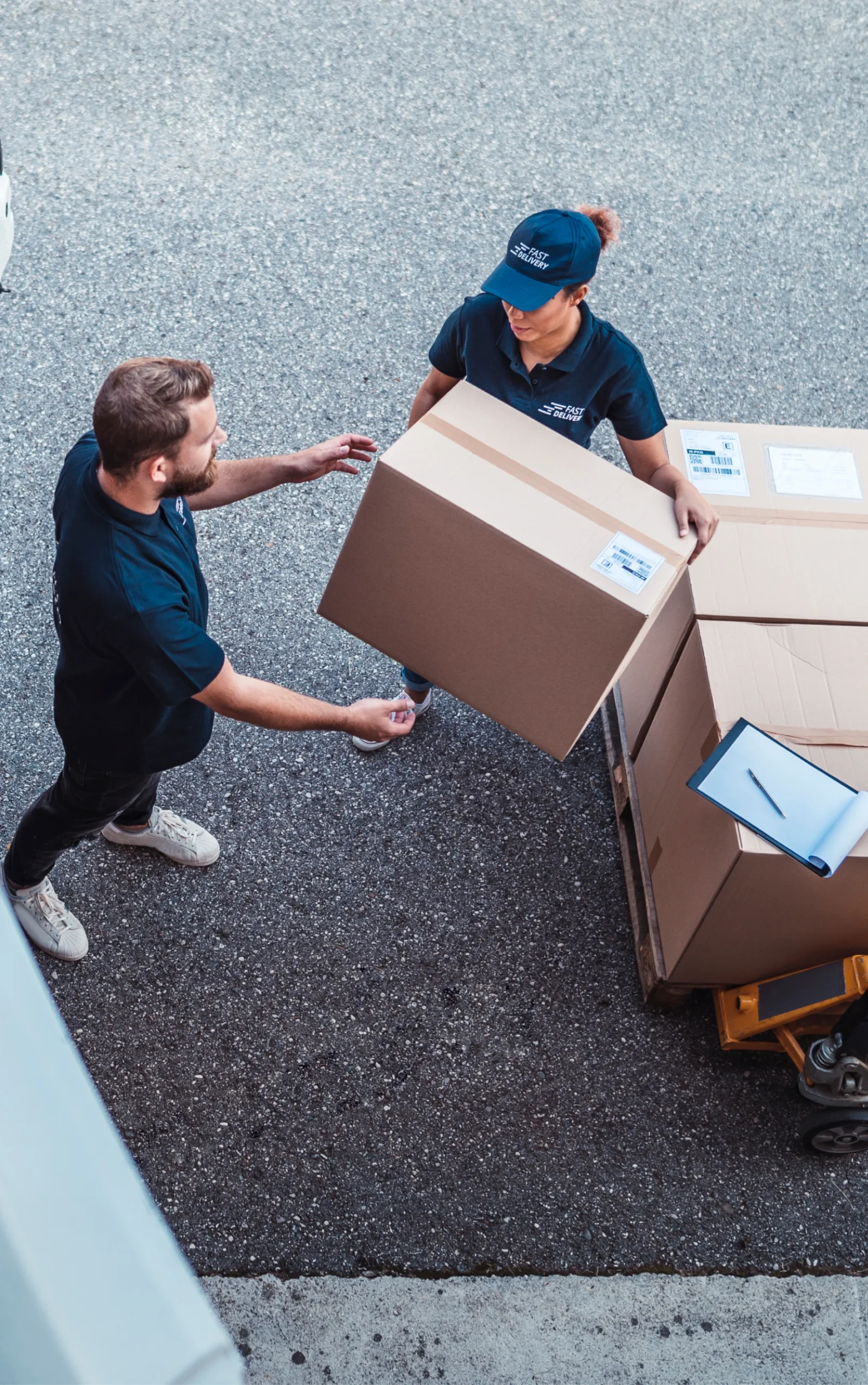 Two workers handling large cardboard boxes outside.