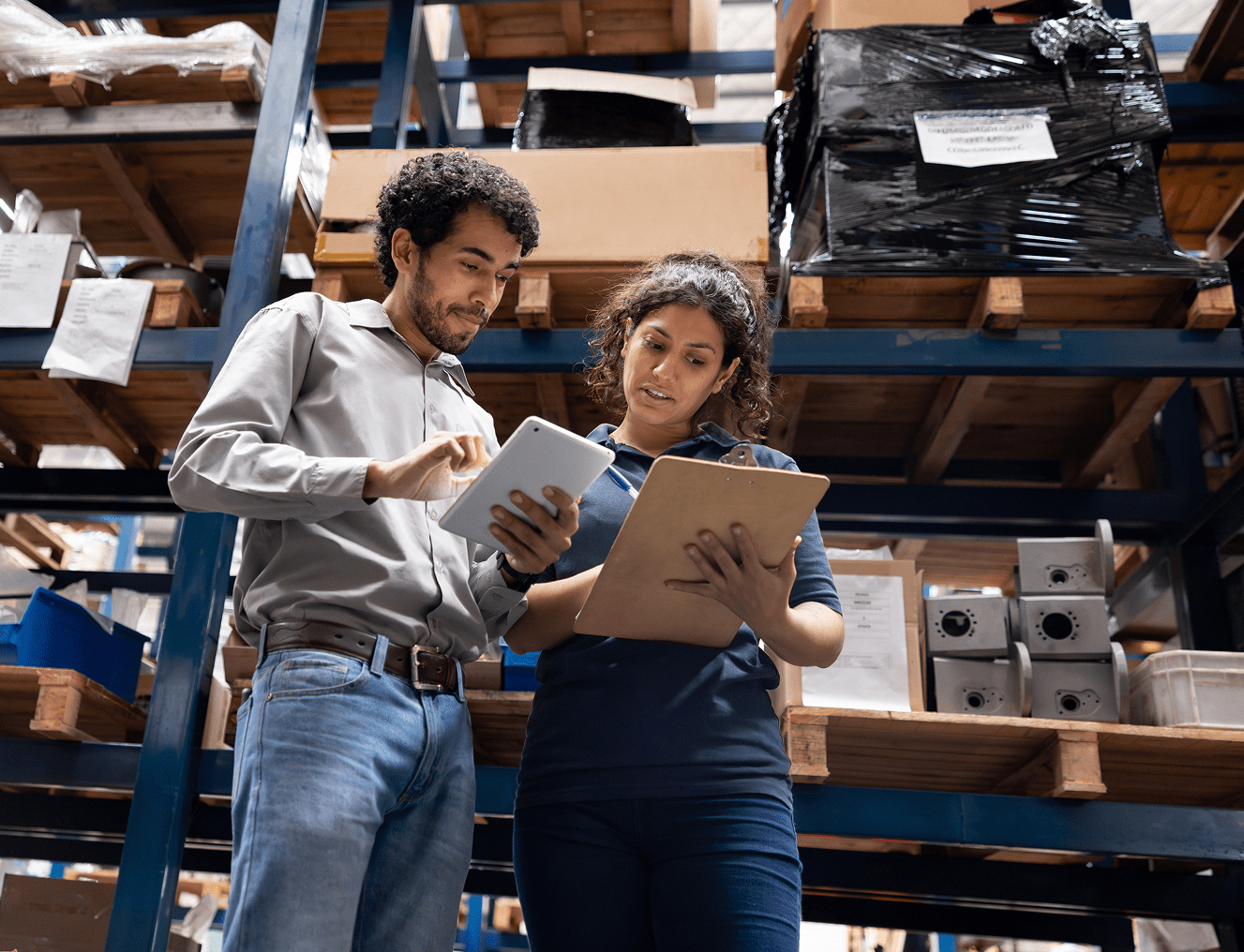 Warehouse workers reviewing documents together on tablets.