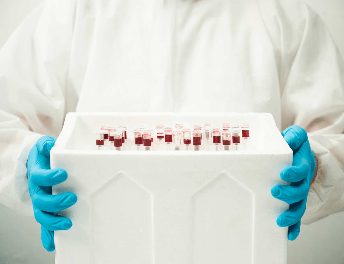 Scientist holding vials in a container.