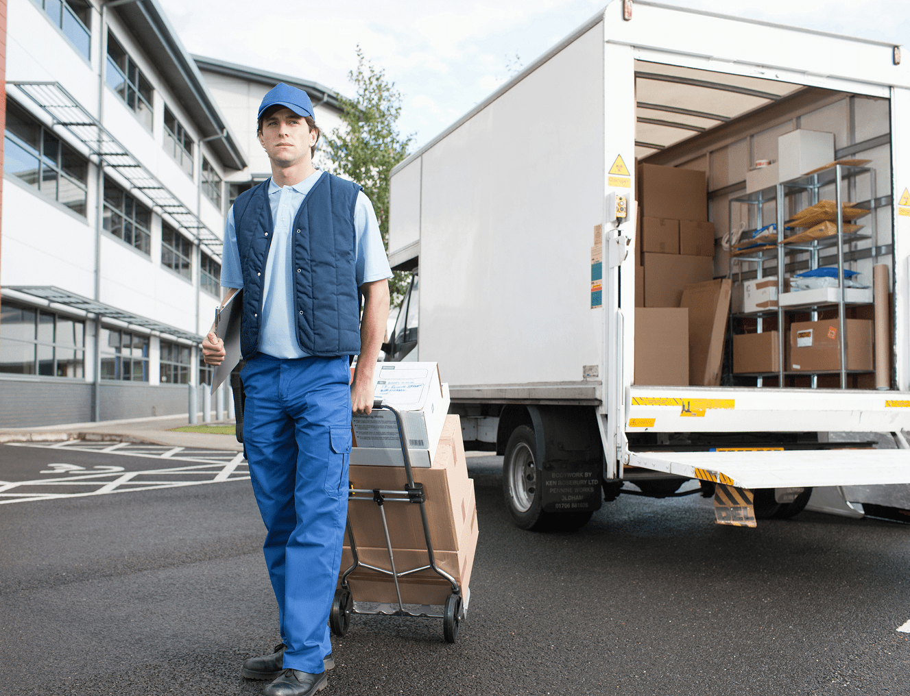 Delivery worker with dolly near truck.